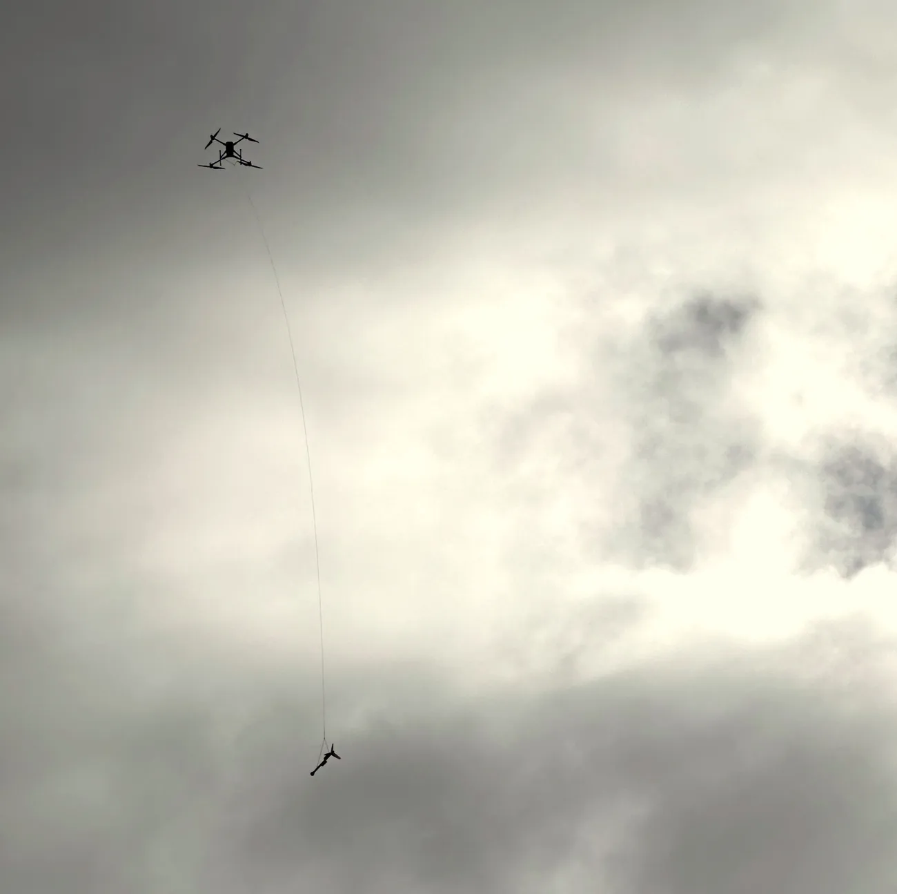 The drone in flight towing the magnetometer bird on a long line below it